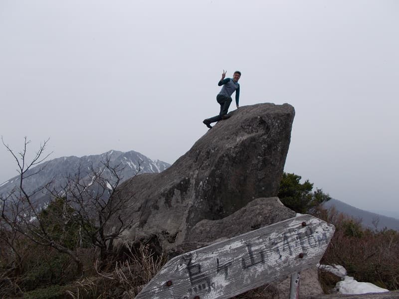 山頂の岩場に登る上田さん